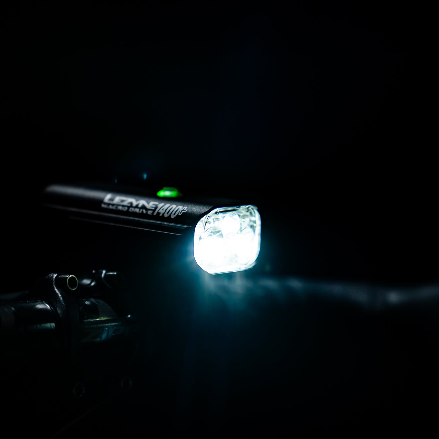 MACRO DRIVE 1400+ front LED bike light mounted on road bike handlebar, delivering strong illumination for cycling after the sun drops.