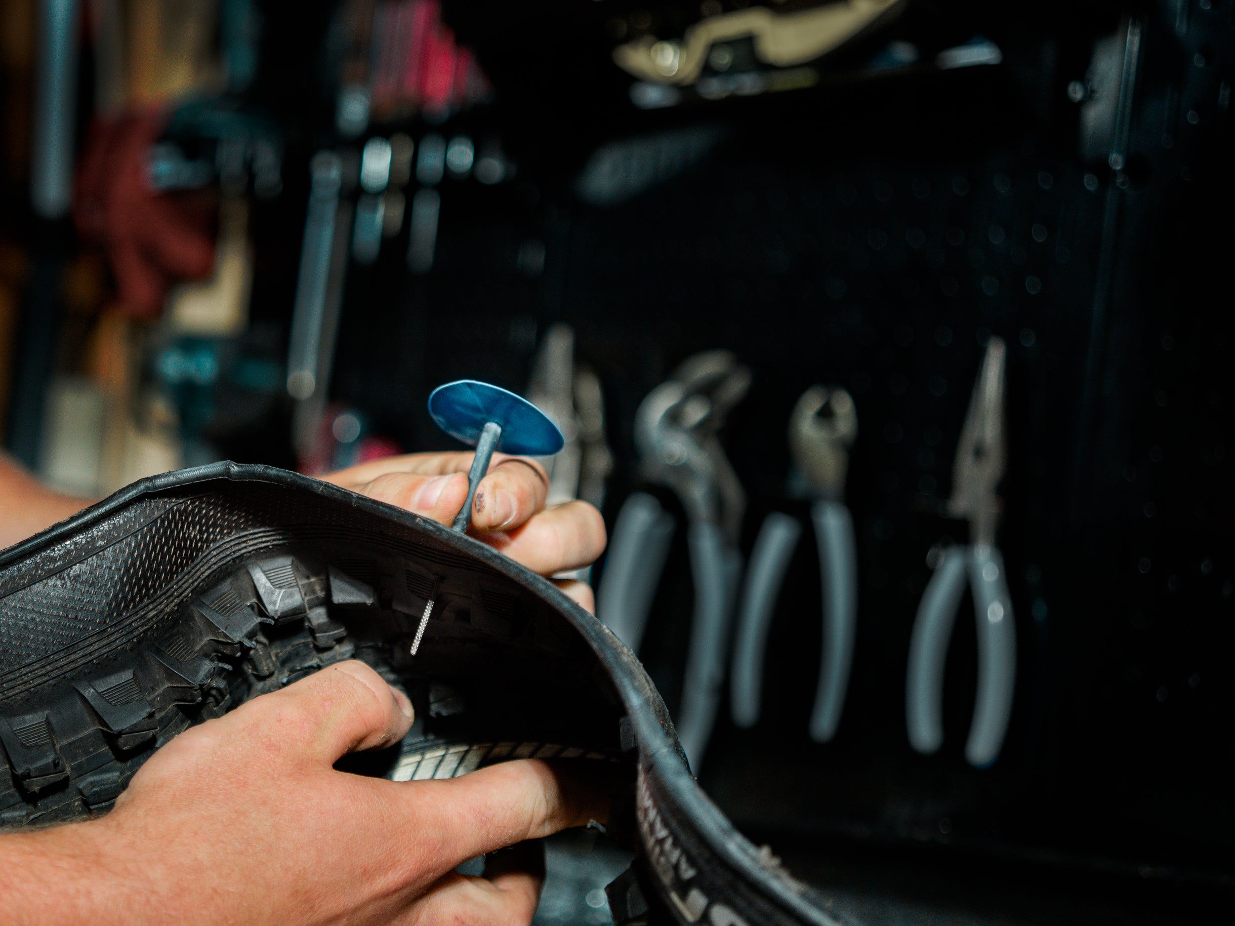 A rider fixing a flat tire using a tubeless tire repair plug from the Lezyne kit.