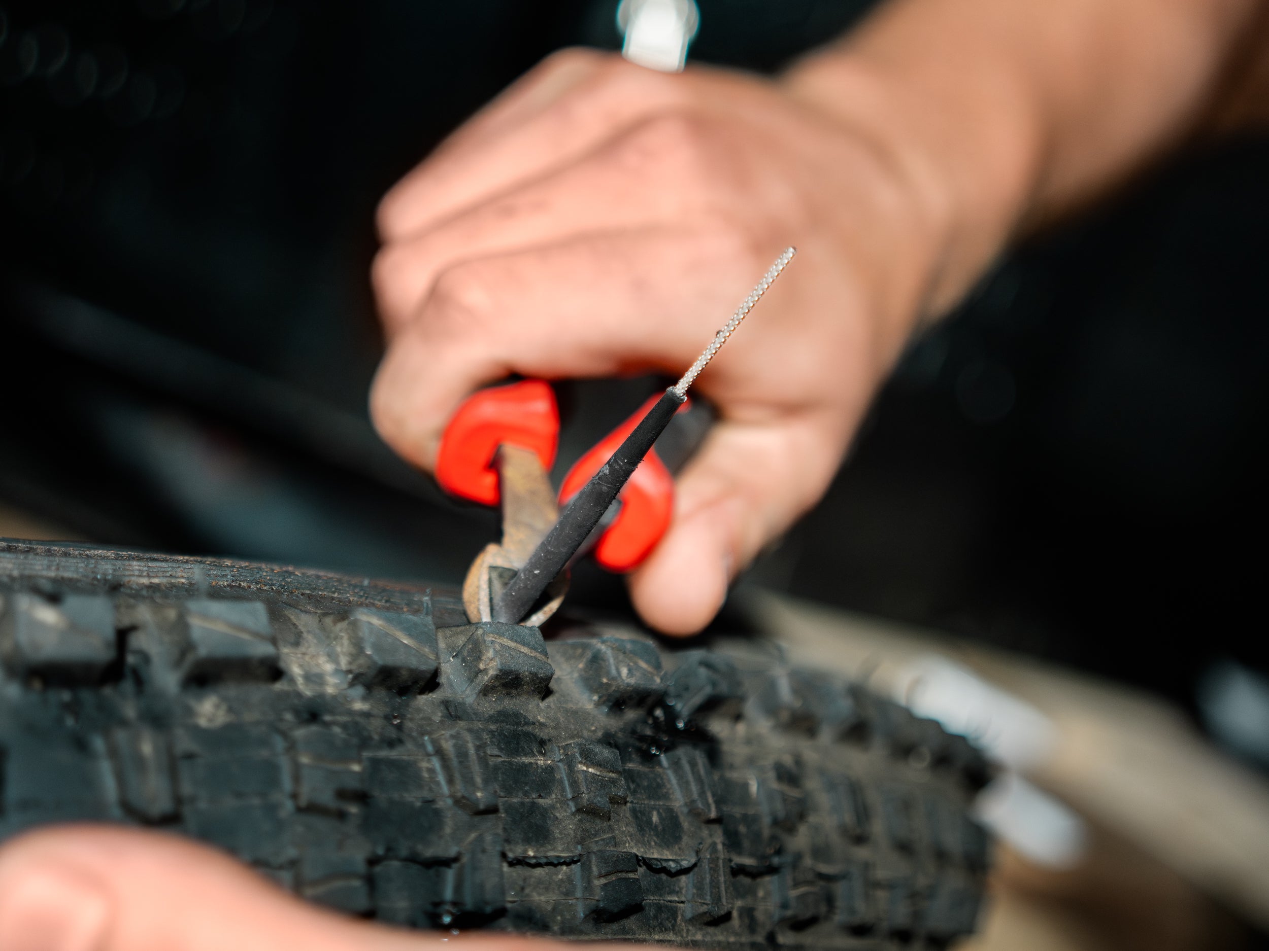 A mtb rider fixing a flat tubeless-ready tire using a tubeless tire repair plug from the Lezyne kit.