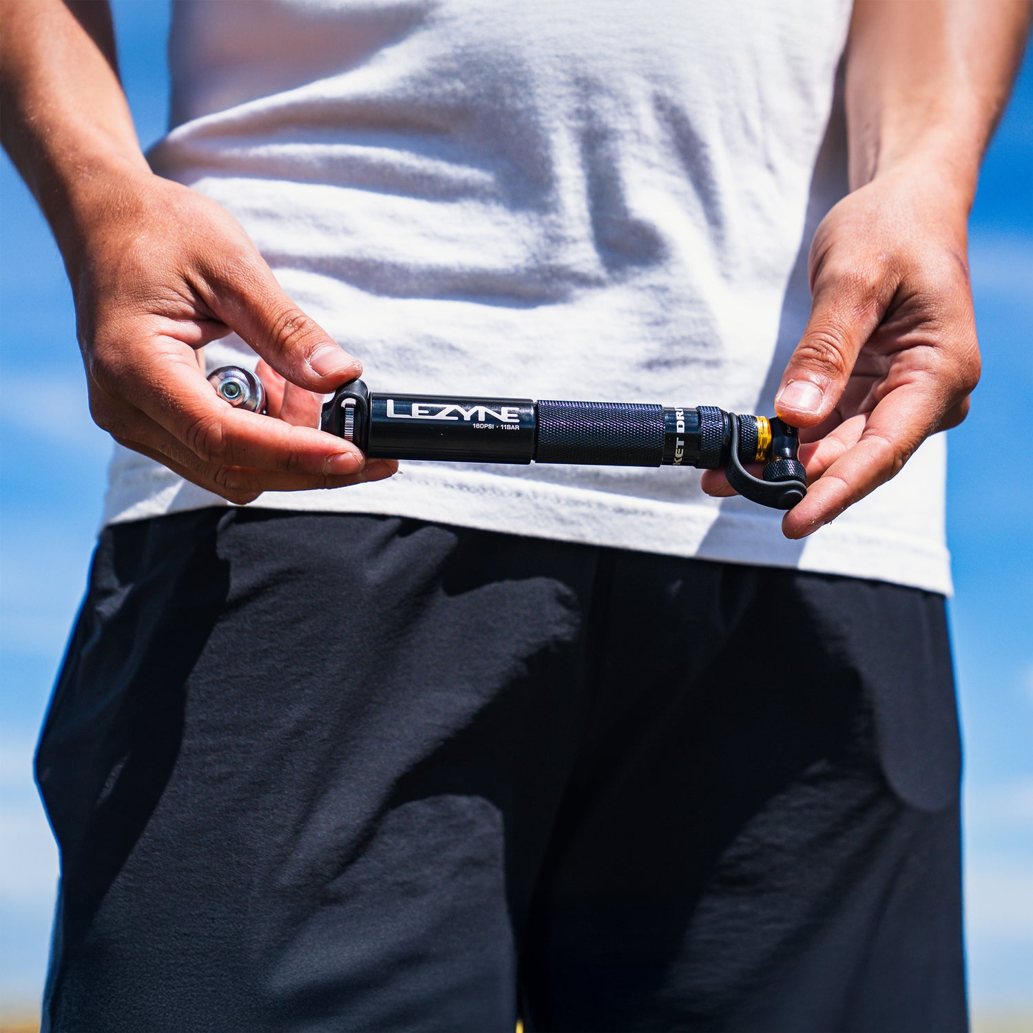 Cyclist holding the Pocket Drive CO2 bike hand pump with its CO2 chuck, showing off its compact size and sleek design.