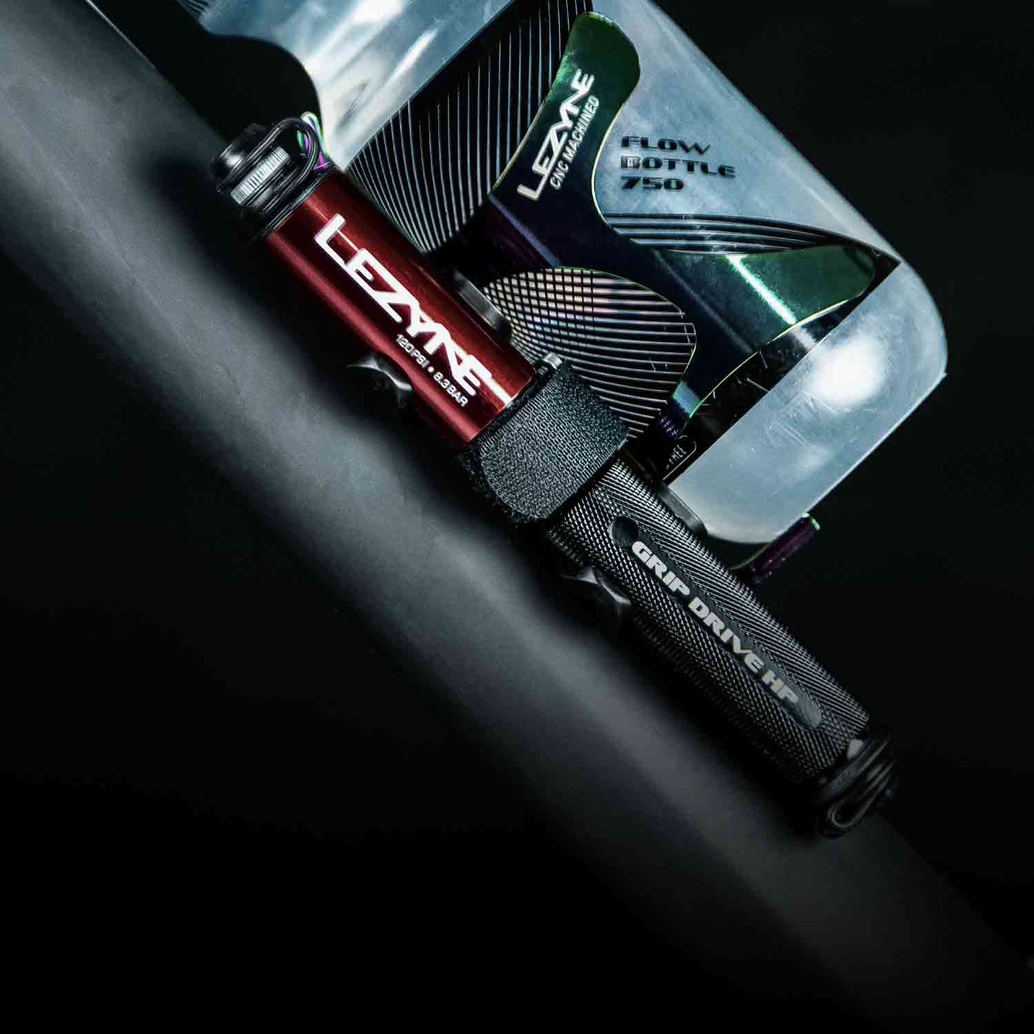 A close up of a hand pump and a water bottle mounted to a bicycle frame.