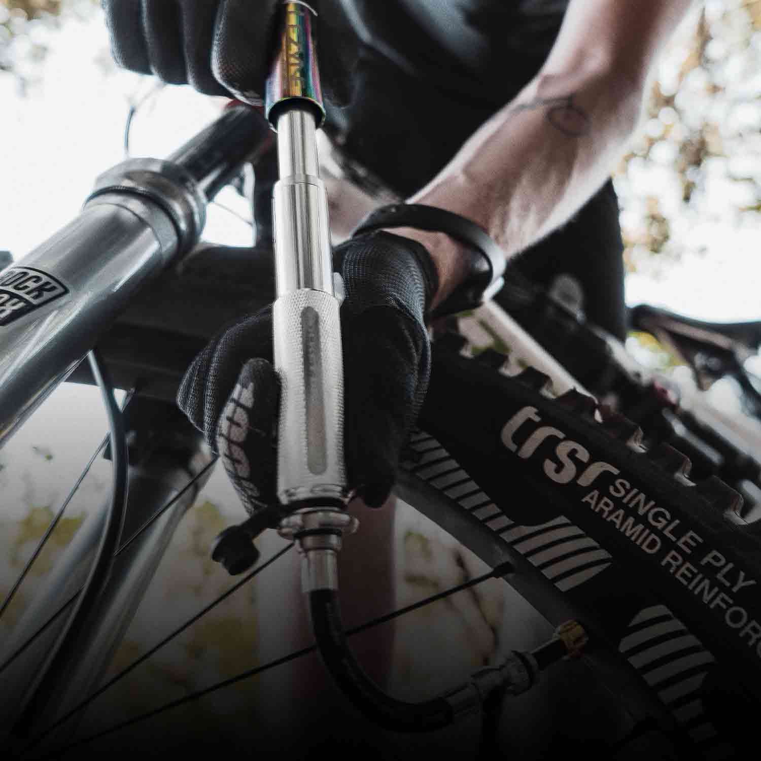 Someone holding a hand pump while inflating a bicycle tire.