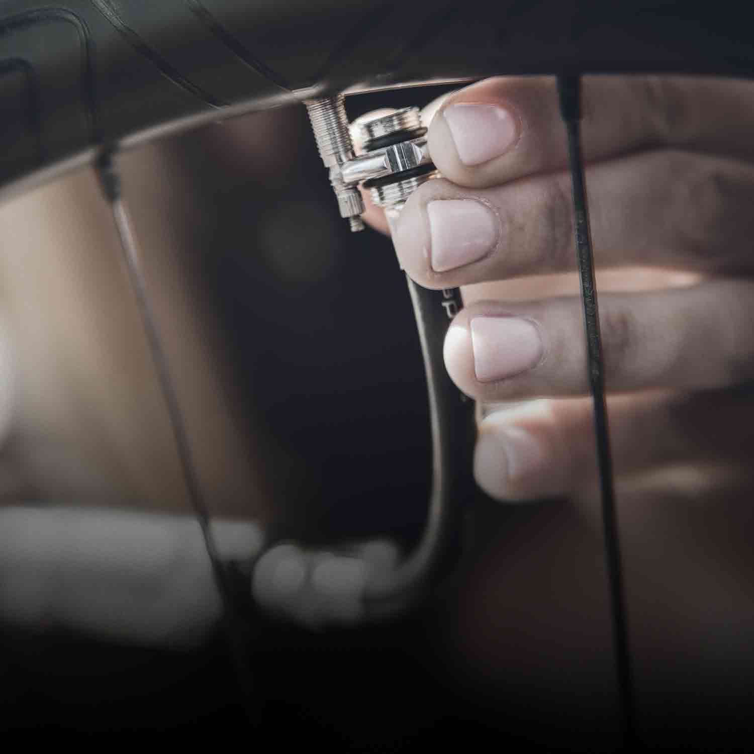 A hand holding an inflation hose near a bicycle tire.