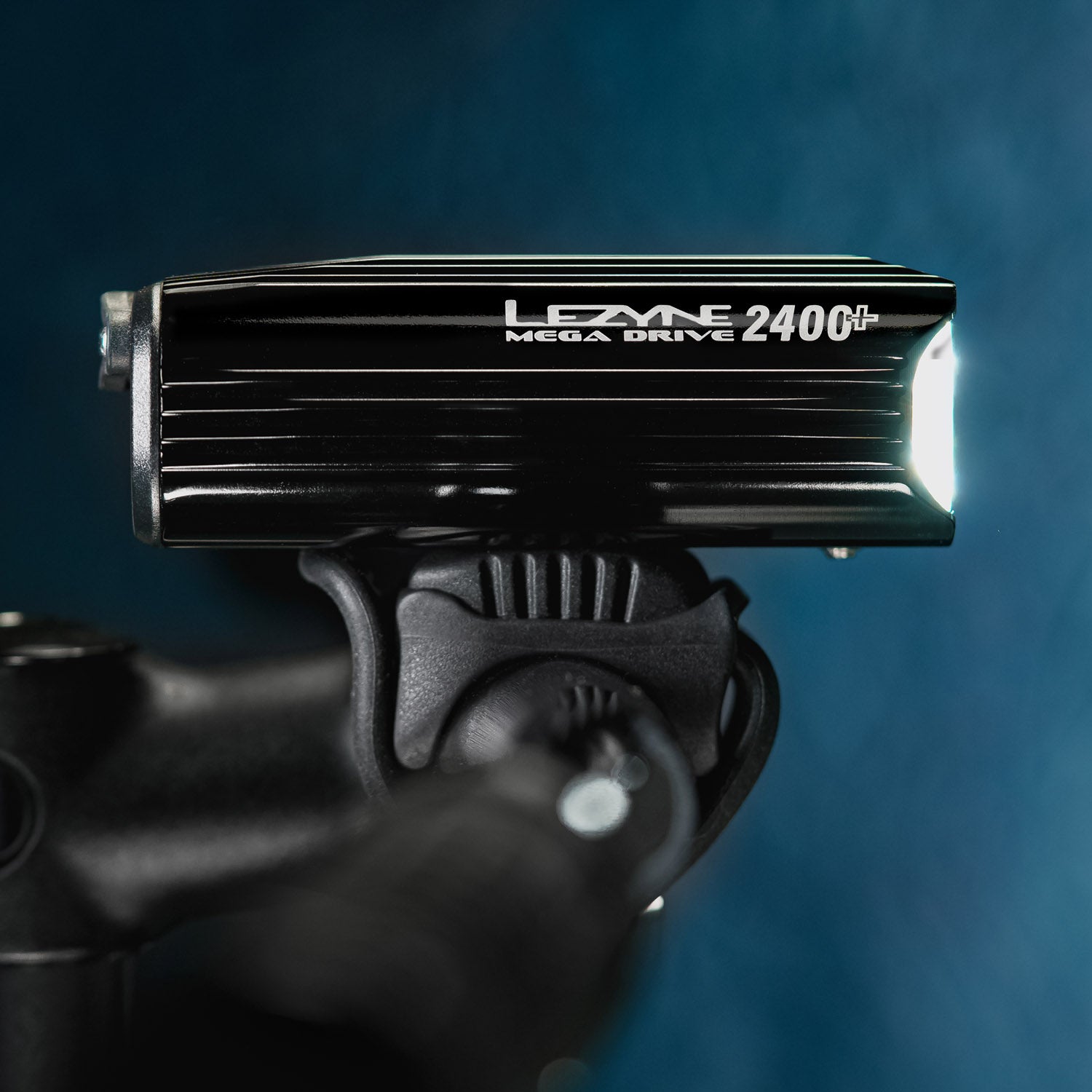 Side view of Mega Drive 2400+ mounted on MTB handlebar, projecting a powerful LED light beam - ideal for night trails.