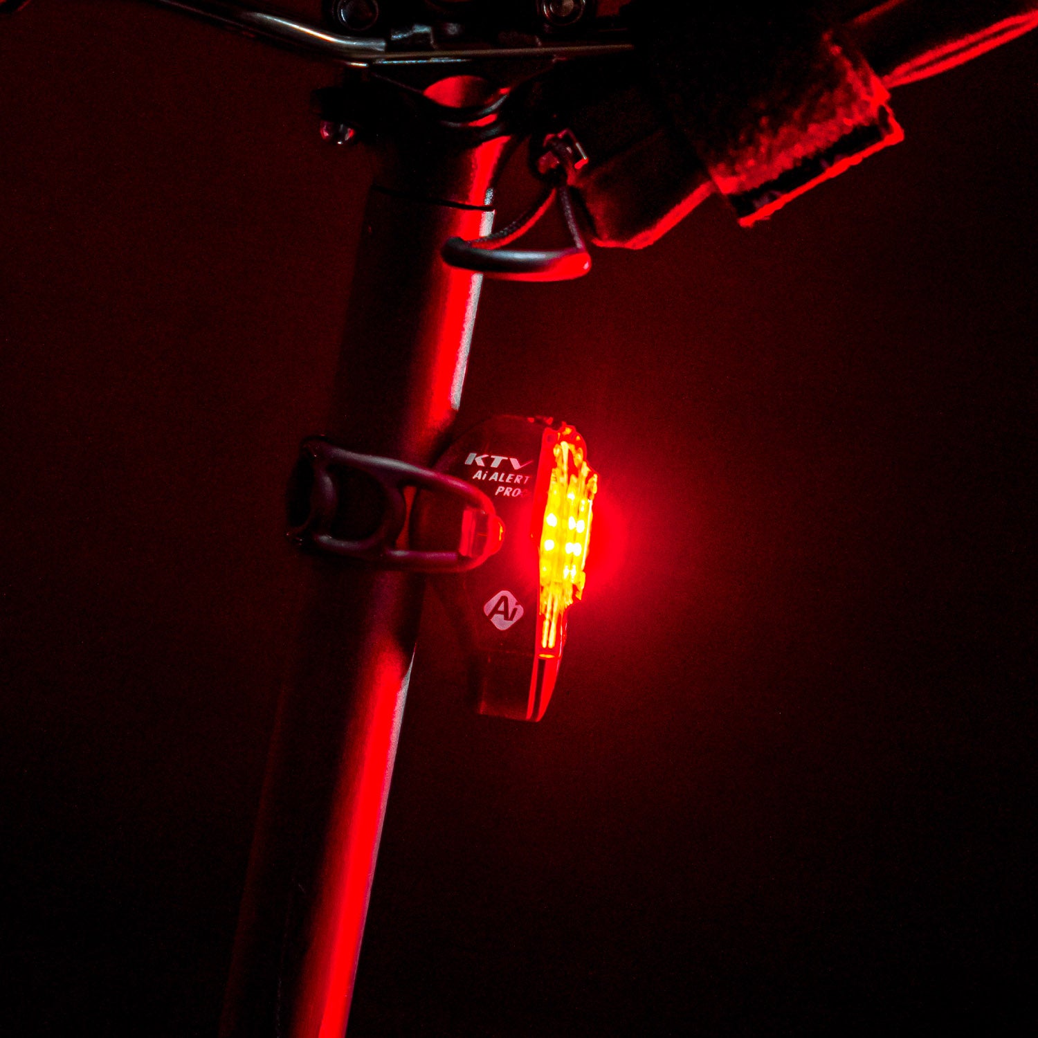 Lezyne KTV Pro+ Ai Alert LED rear bike light, profile view, mounted on road bike seat post, emitting powerful red light.