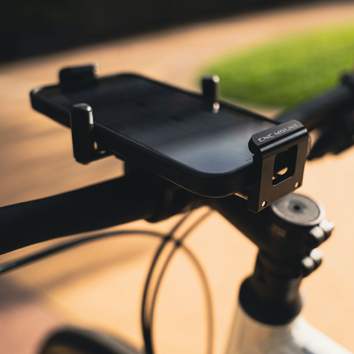 CNC Phone Mount securely attached to bike handlebars, showcasing stable hold and premium aluminum construction.