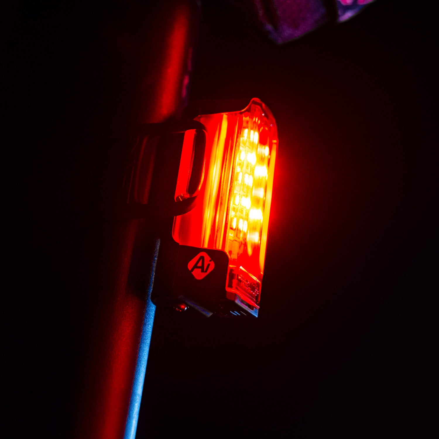 Close-up of Lezyne Strip Pro Ai Alert 400+ smart LED rear bike light mounted on a road bike saddle bar, emitting bright red light for high visibility in traffic.