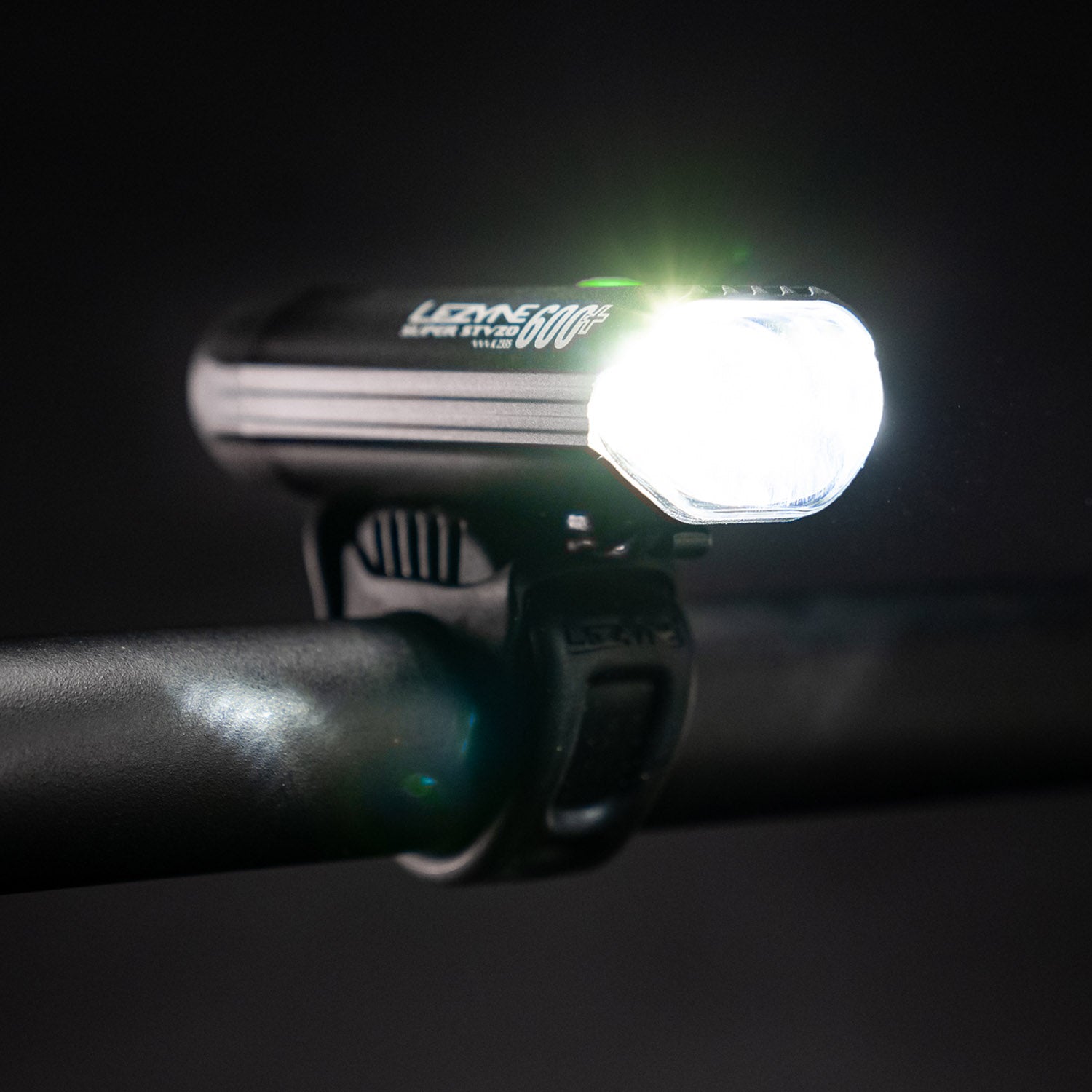 Side view of the Lezyne Super StVZO 600+ Bike Light, mounted on the handlebars, emitting a bright white beam.