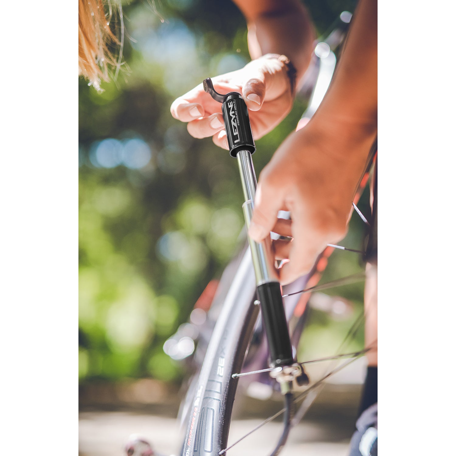Cyclist using Pressure Drive bike hand pump on roadside, demonstrating high-pressure inflation performance in real-world setting.