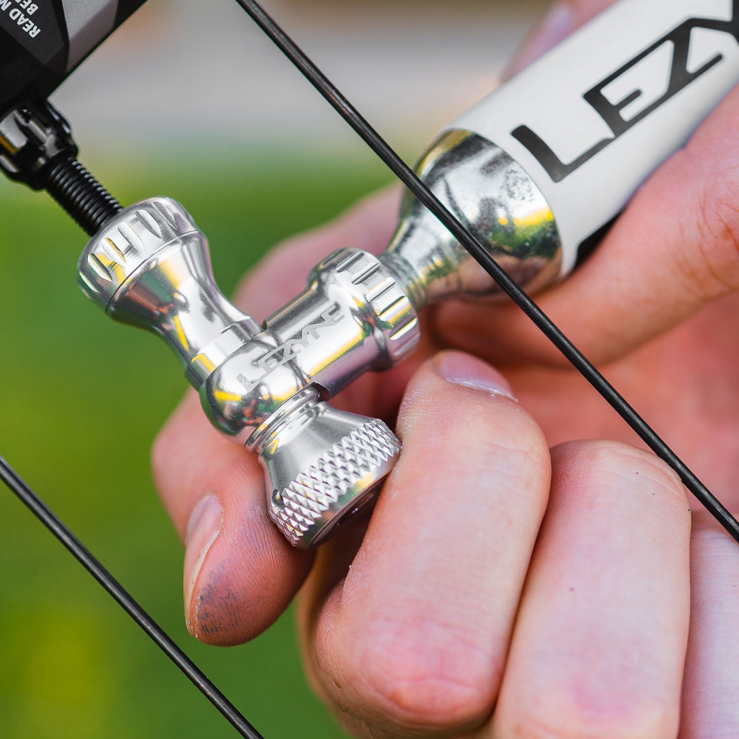 Cyclist using silver Control Drive CO2 inflator on a road bike, showing easy inflation with twist knob and Presta valve fit.