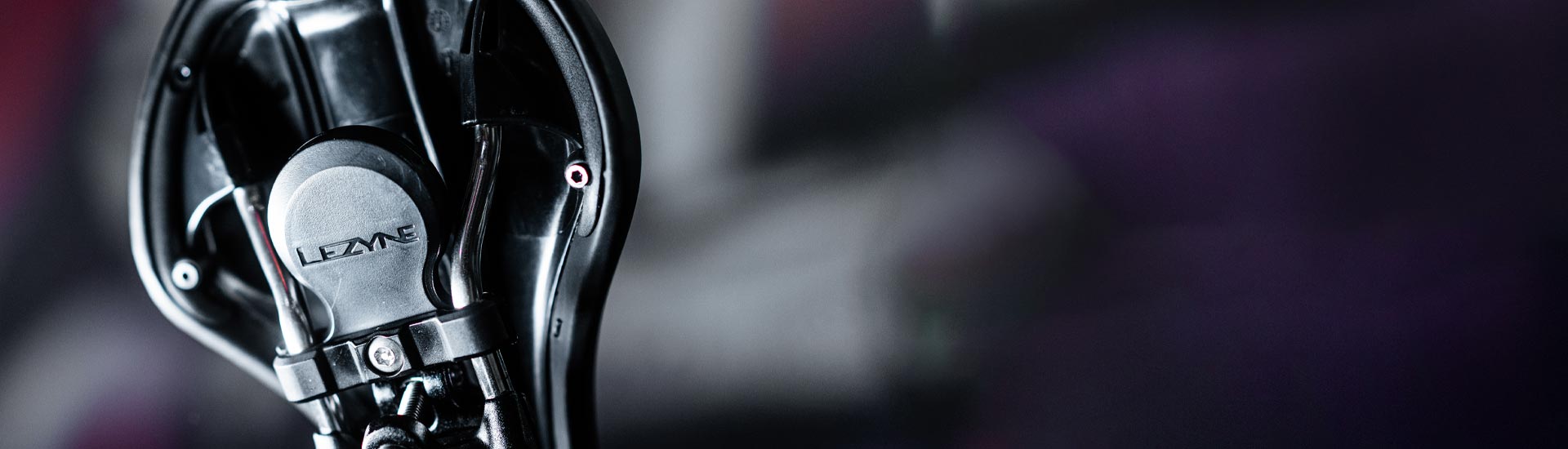 A small circular object mounted to the bottom of a bicycle seat with the word Lezyne printed on it.