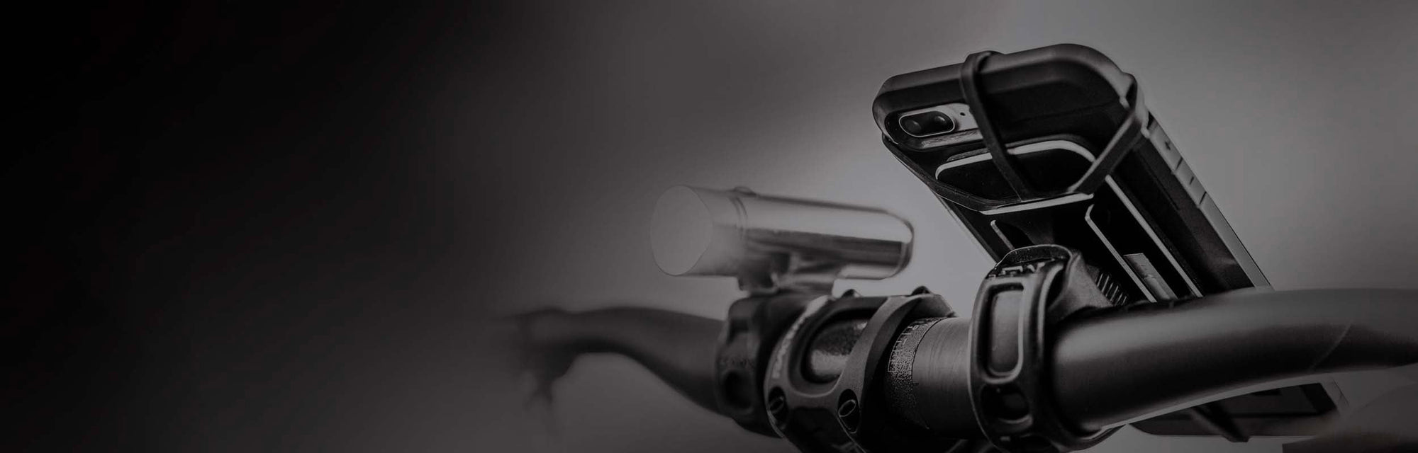 A phone and a light mounted to bicycle handlebars.