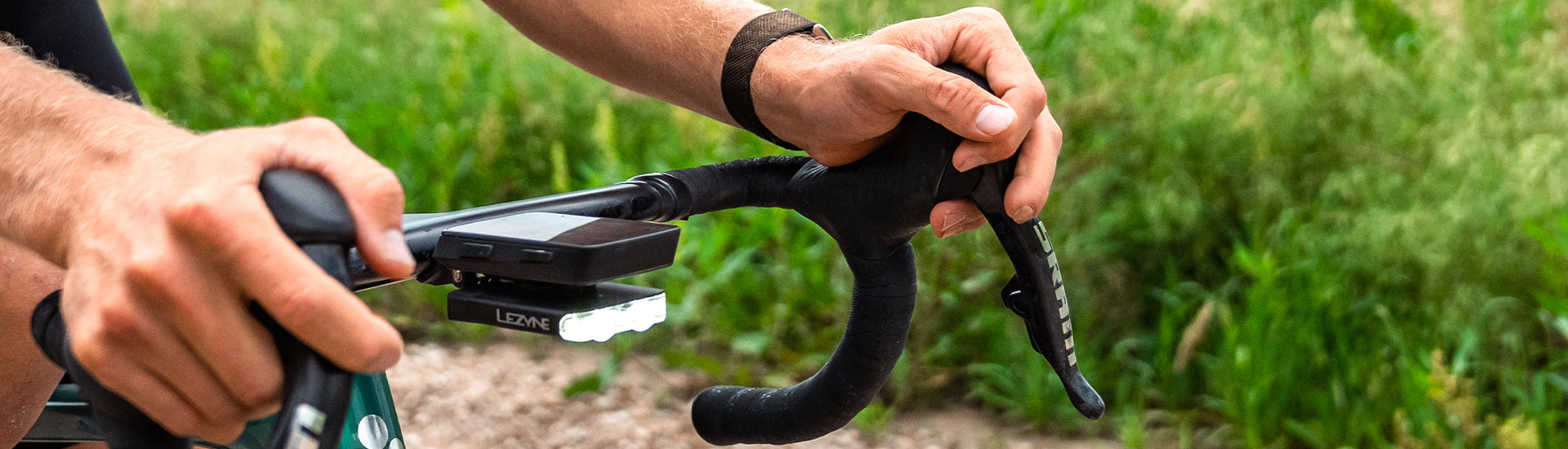 Someone pressing the button on a front light mounted on bicycle handlebars