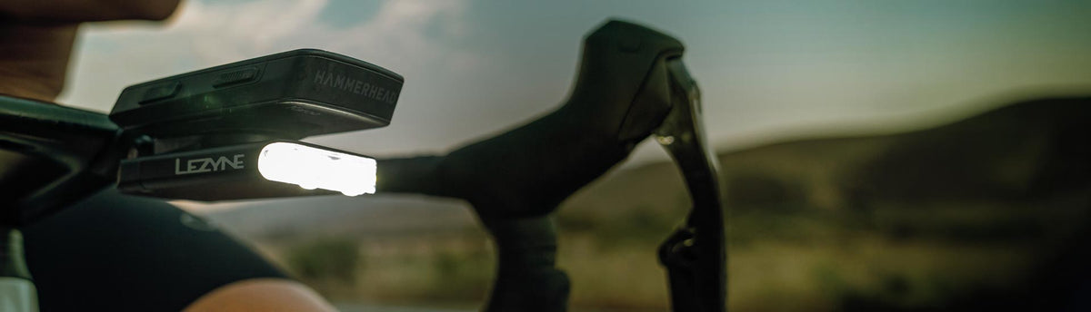 Someone pressing the button on a front light mounted on bicycle handlebars