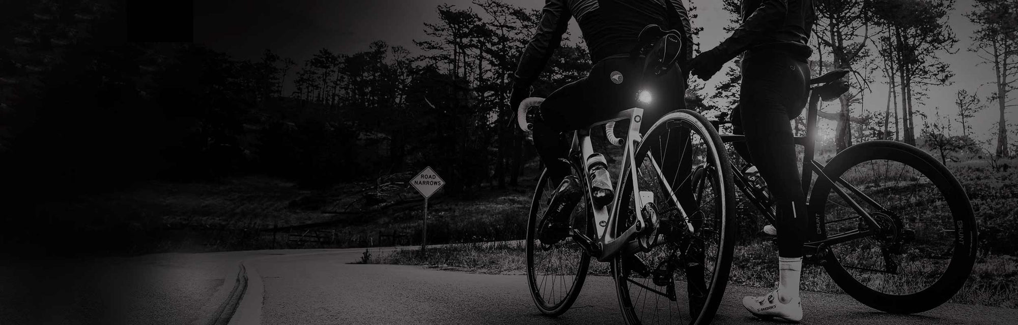 The back side of 2 people stopped on bicycles with bright rear lights.
