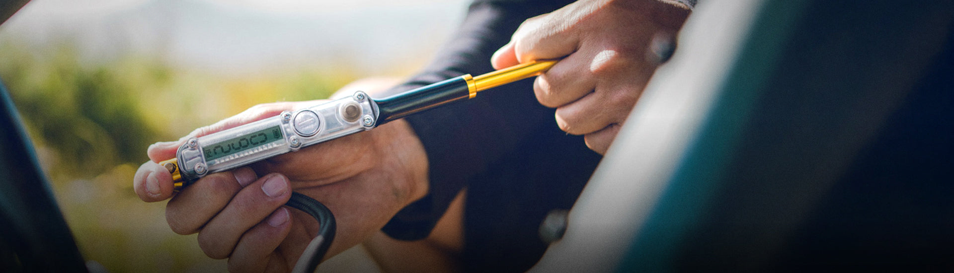 Gloved hands holding a digital pressure gage next to a bicycle tire.