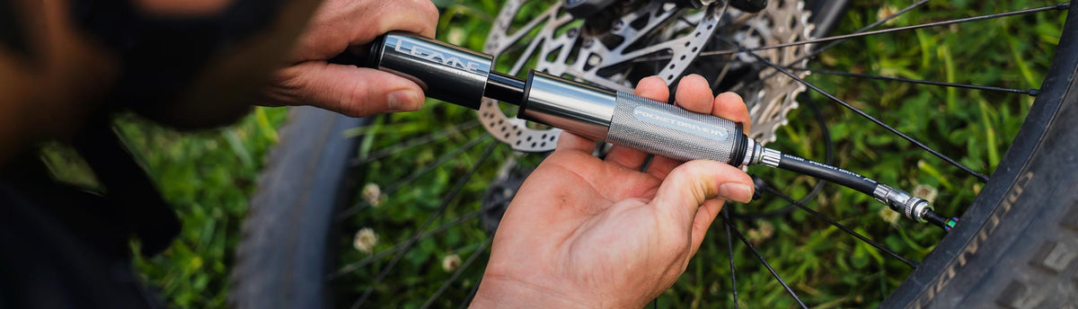 Gloved hands holding a digital pressure gage next to a bicycle tire.