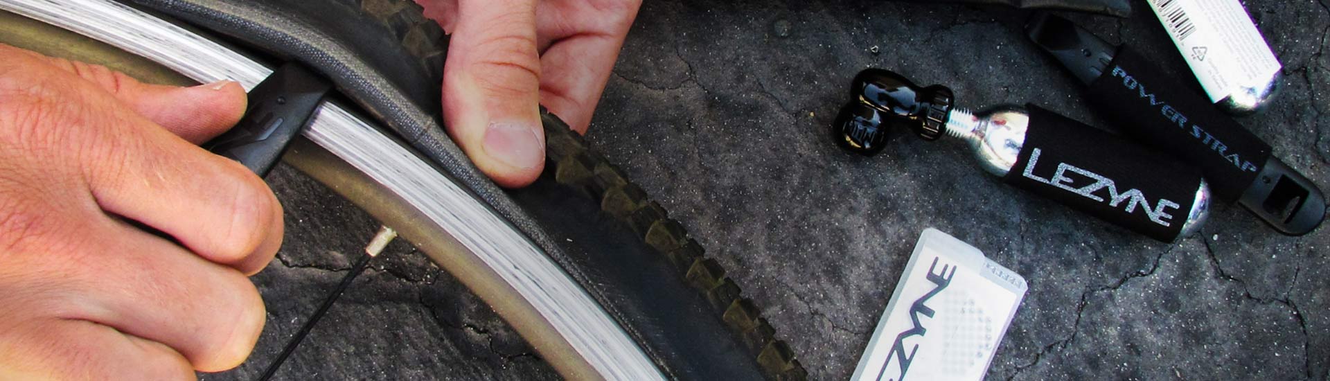 Someone using a tool to remove a bicycle tire from a rim.