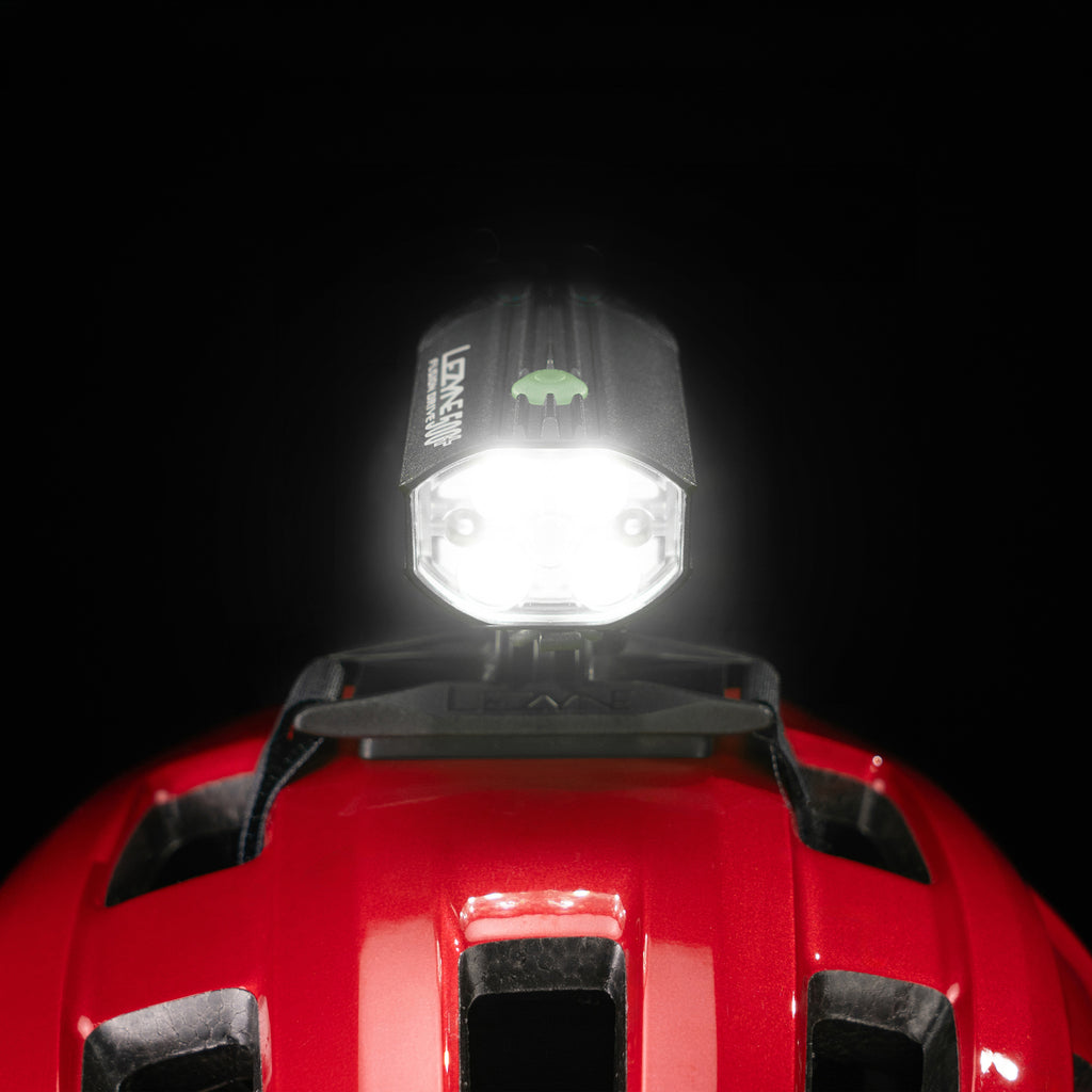 Front close-up studio shot of the Lezyne Helmet Fusion Drive 500+ with bright light beam mounted on a red helmet 