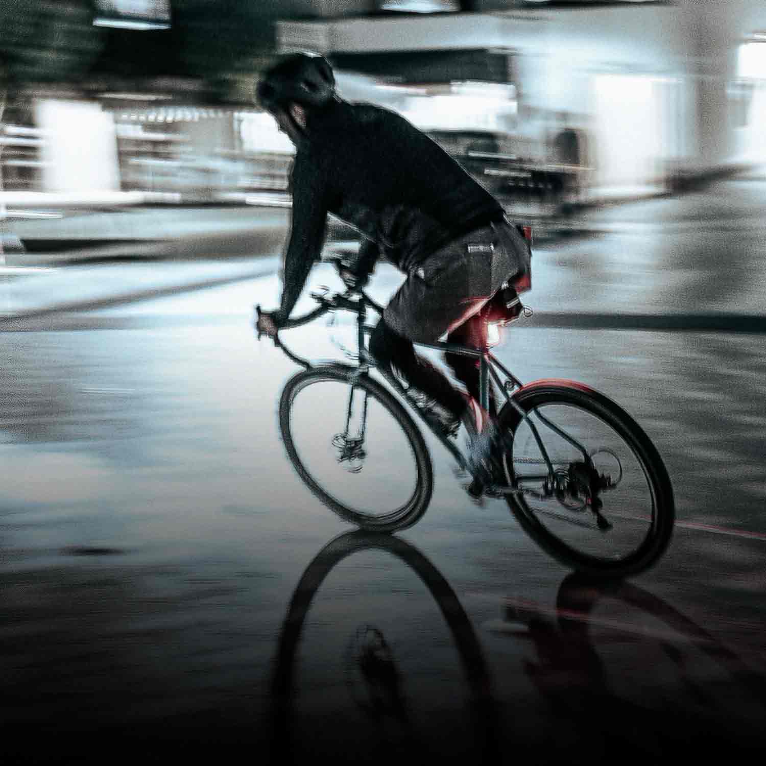 Someone riding a bike on a slick surface with a bright rear light mounted on their seat post. 