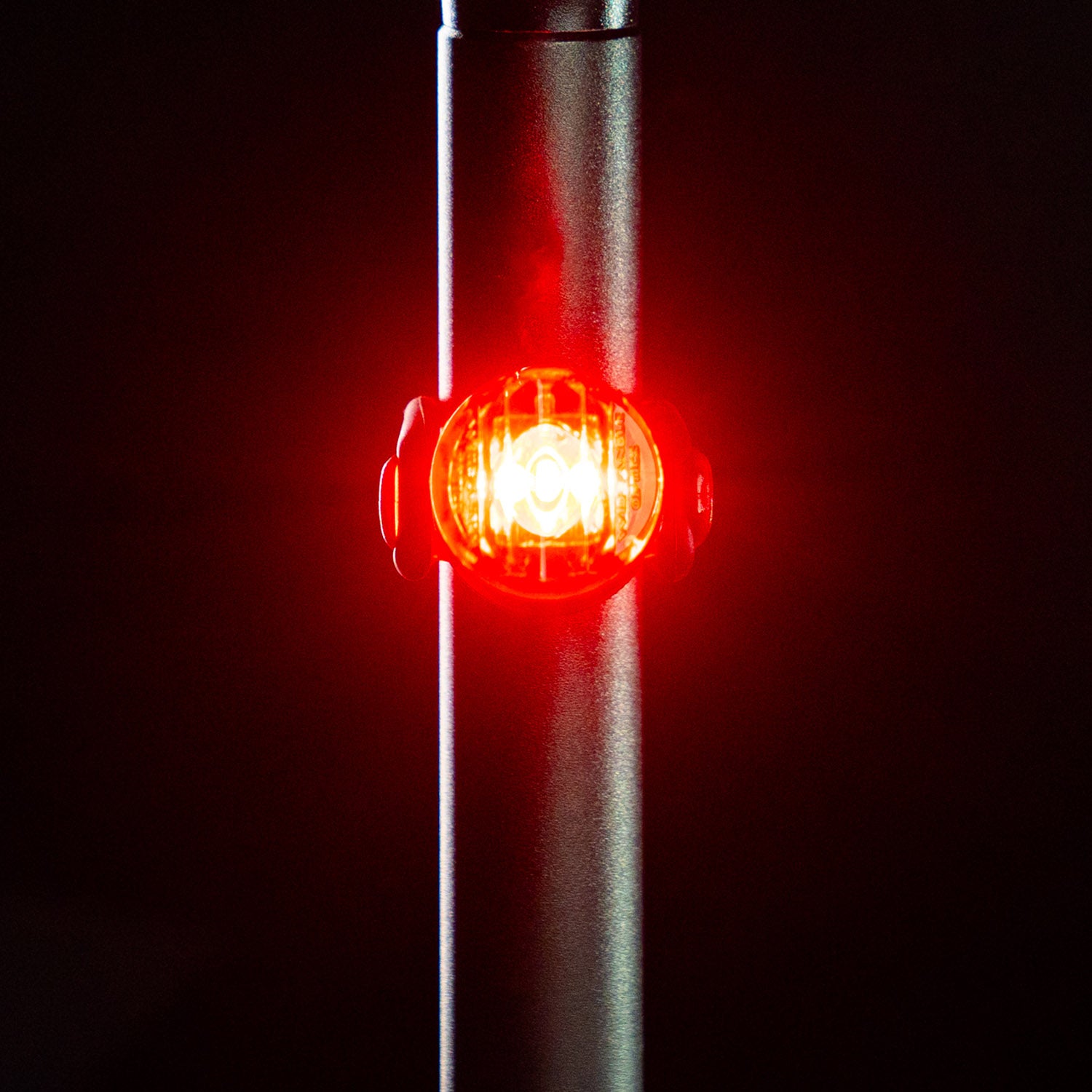 Front view of the circular Lezyne Femto USB Rear StVZO LED light, emitting a strong red light, mounted on the seatpost.