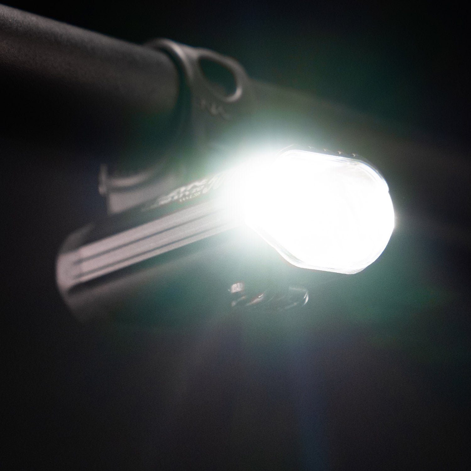 Side view from below of the Lezyne Macro StVZO 500+ Reverse headlight, mounted upside down on the handlebars, emitting a bright white beam.