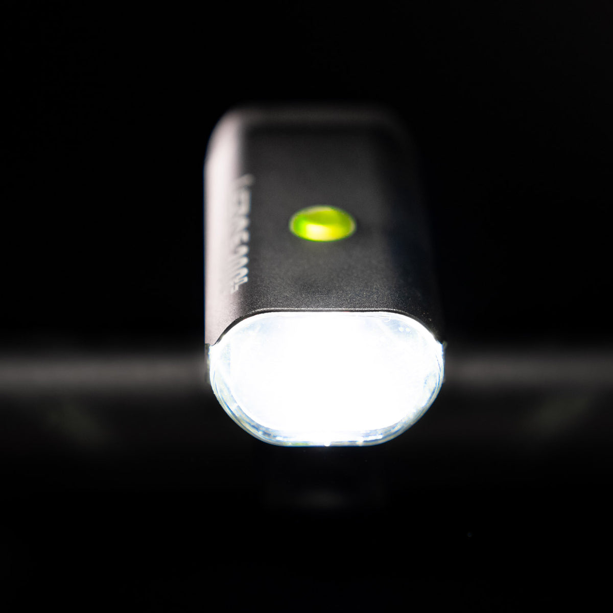 Front view of the Lezyne Micro StVZO 300+ LED bicycle light, facing the viewer with a green circular power light on top, mounted on the handlebars.