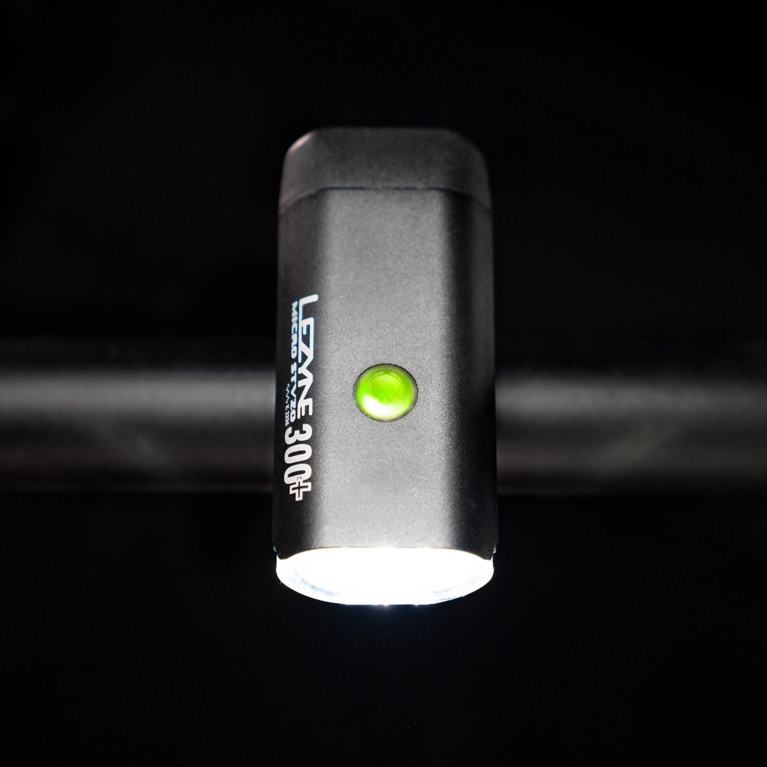 Top-down view of the Lezyne Micro StVZO 300+ headlight with a green lit power button on top of the housing, mounted on the bike handlebars.