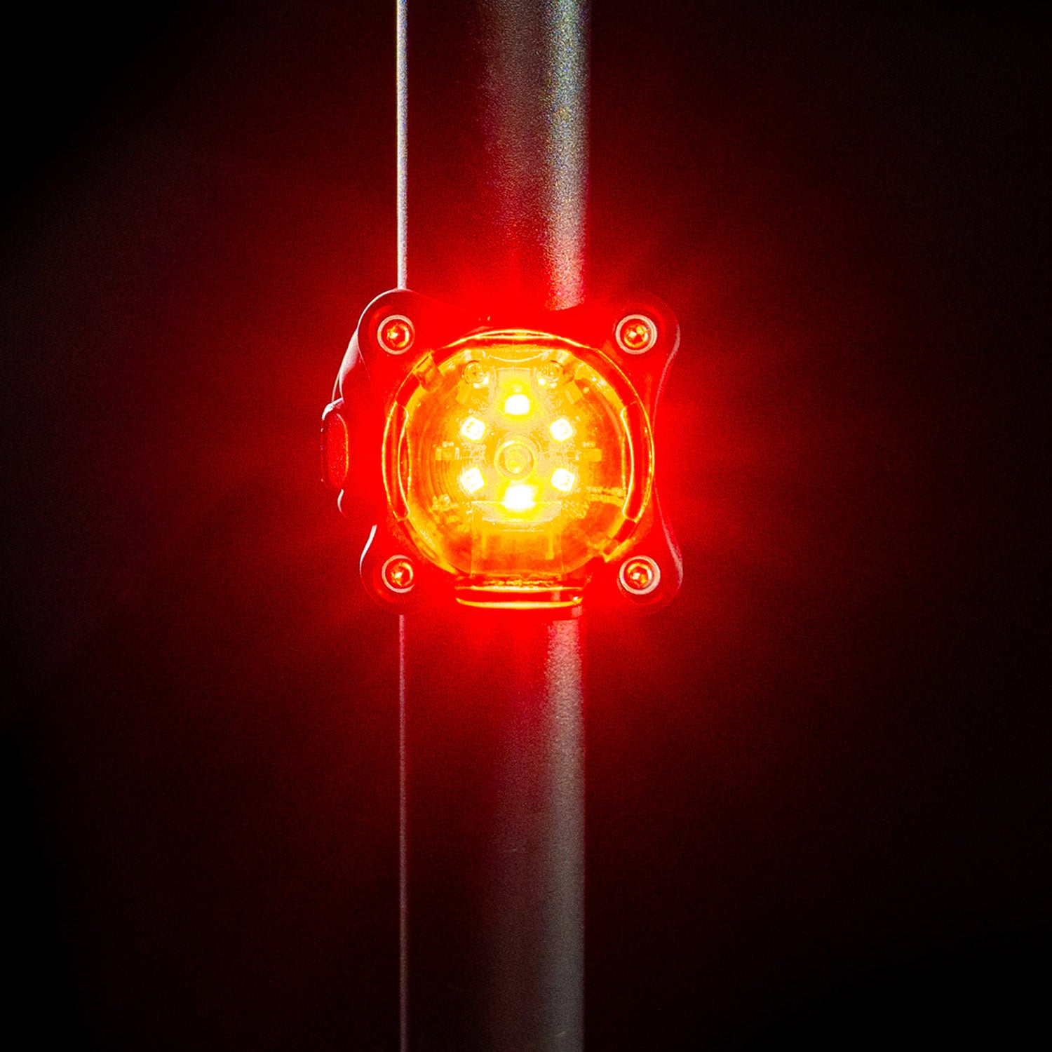 Close-up front view of the small, round Lezyne Zecto StVZO Rear bike light, emitting a bright red light, mounted on the seatpost.