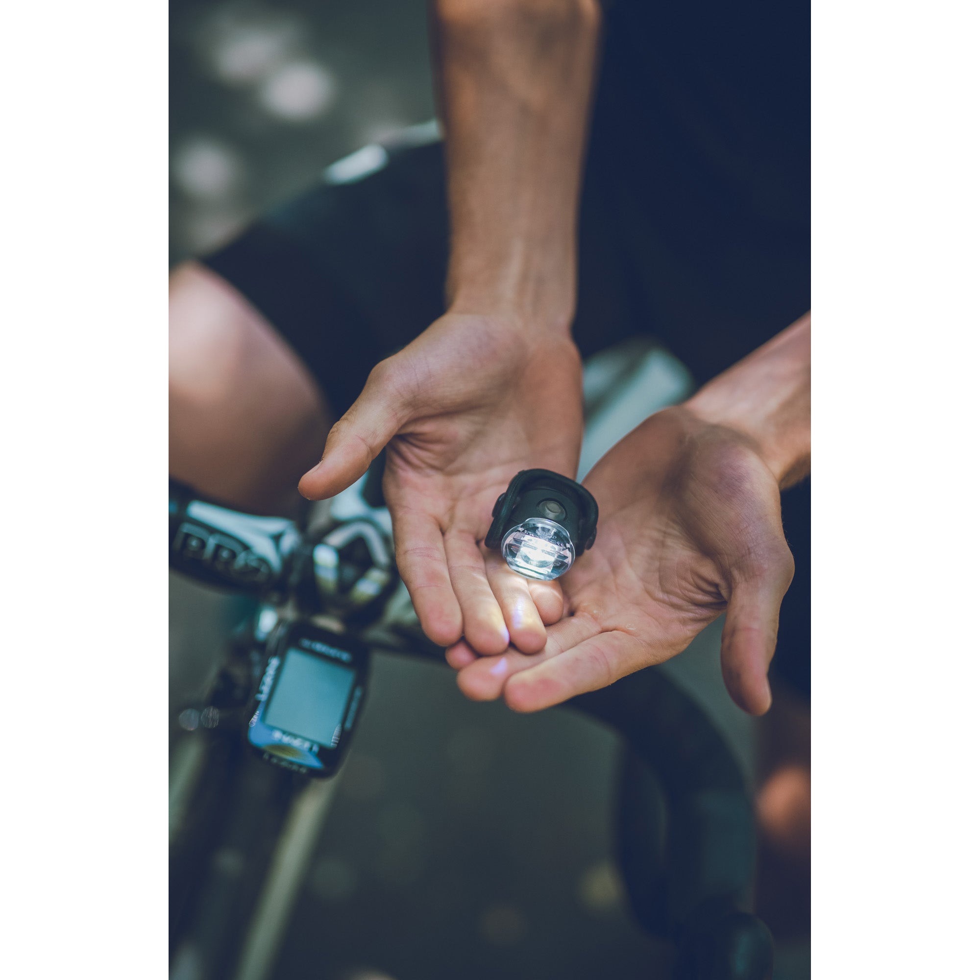 Cyclist holding a Femto USB Drive front bike light in the palm of his hands.